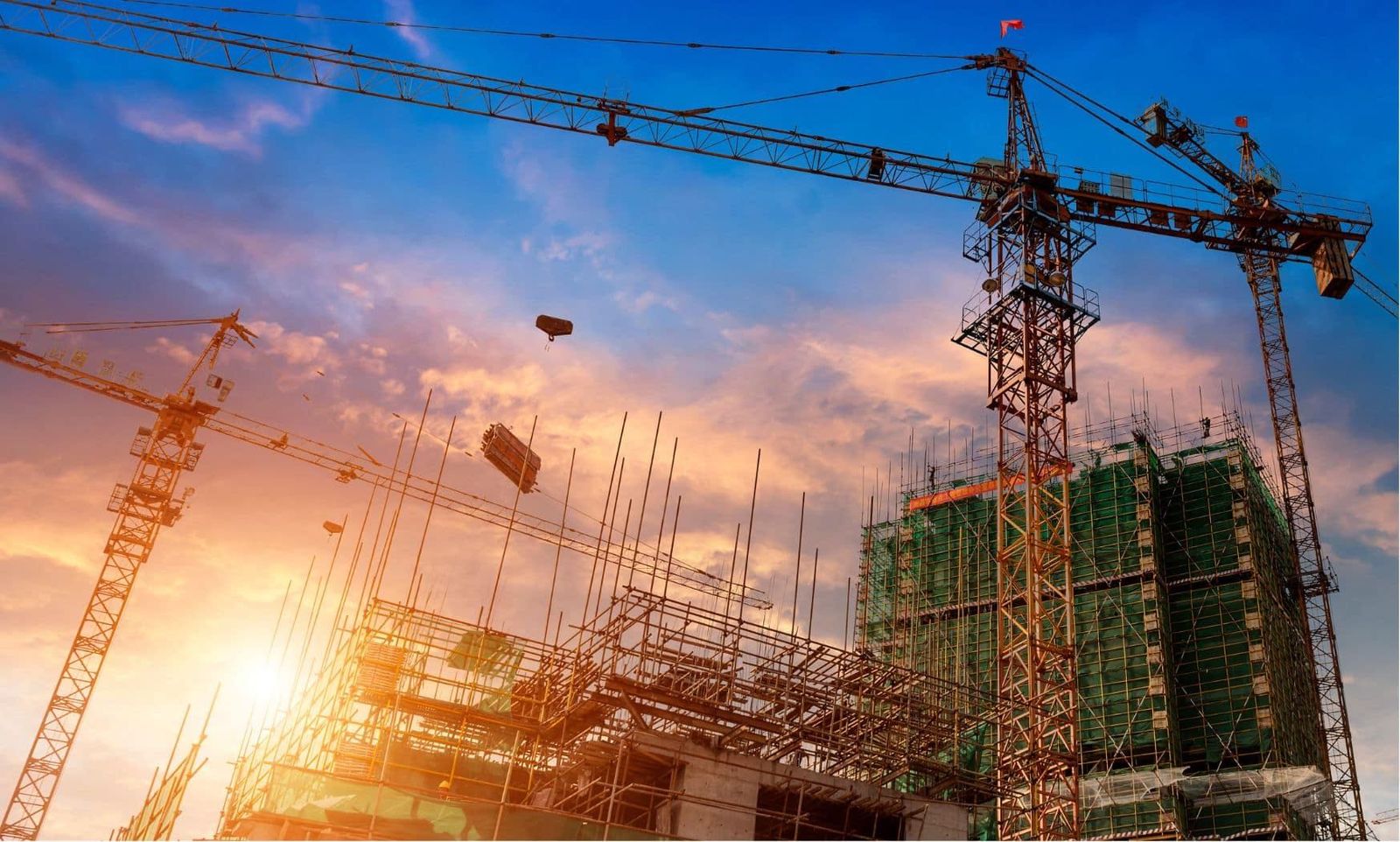 Tower cranes over a construction site at sunset